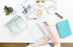 A lady writing on a desk with all her stationary items laid out